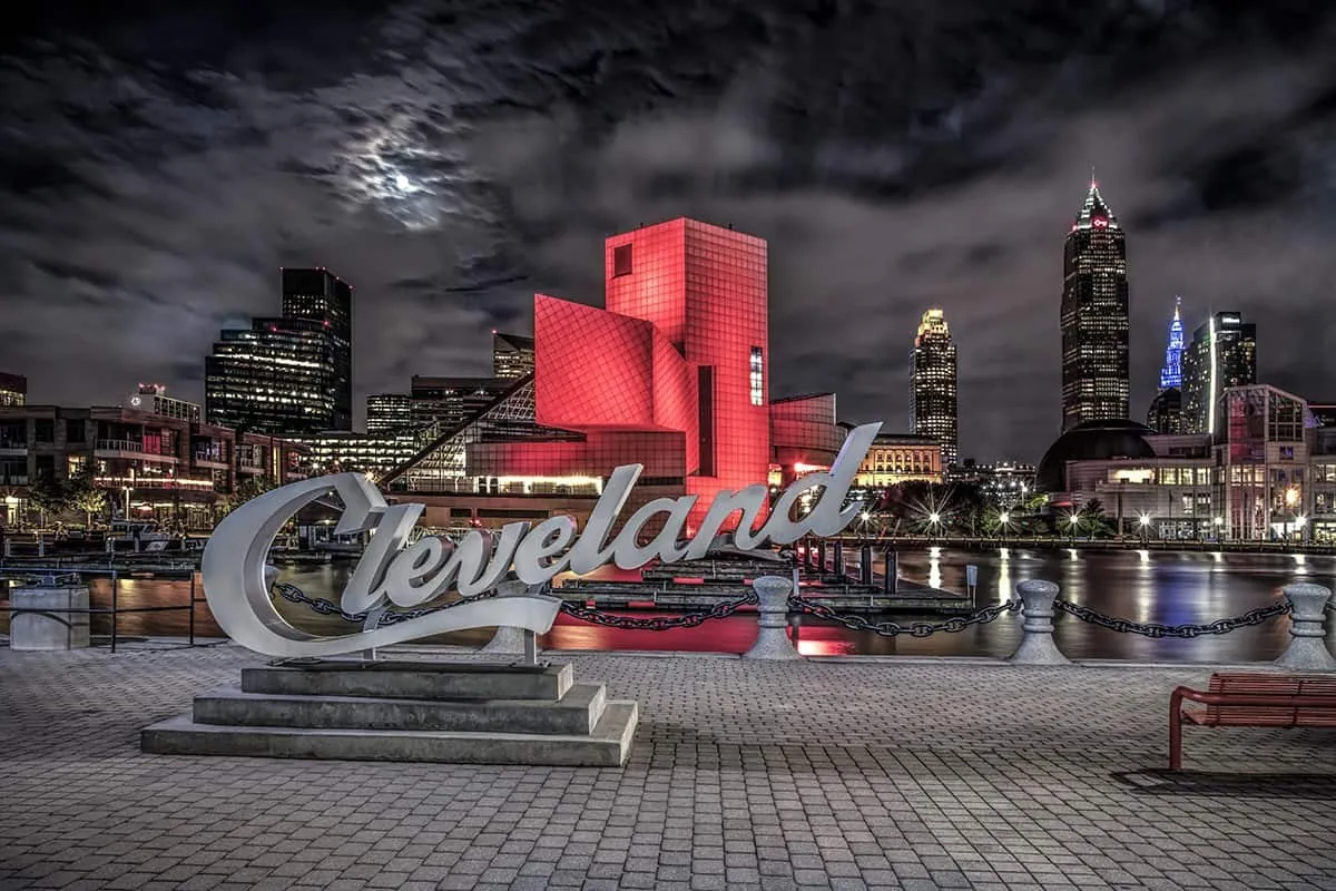 Stock photo by Dan Cleary: the Cleveland script sign at night, with the Rock and Roll Hall of Fame lit red and the downtown skyline behind